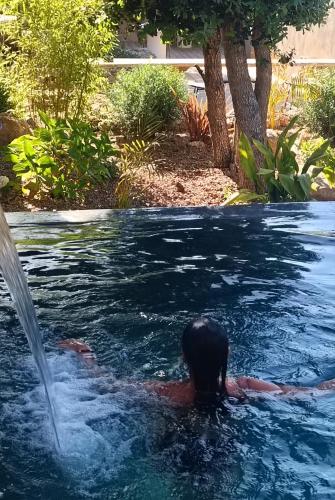 a person swimming in a pool with a fountain at Hôtel Les Suites Du Maquis in Bonifacio