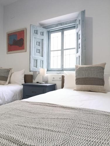 a white bedroom with two beds and a window at Mina25 by 7Escalones in Rota