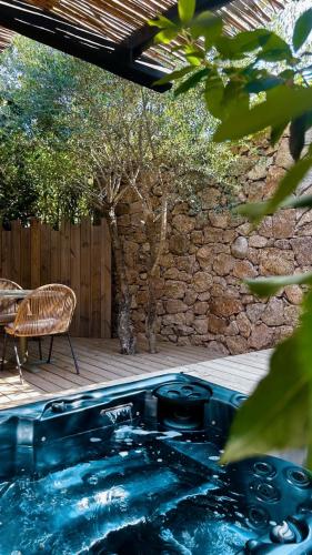 a swimming pool in a yard with a table and a chair at Hôtel Les Suites Du Maquis in Bonifacio