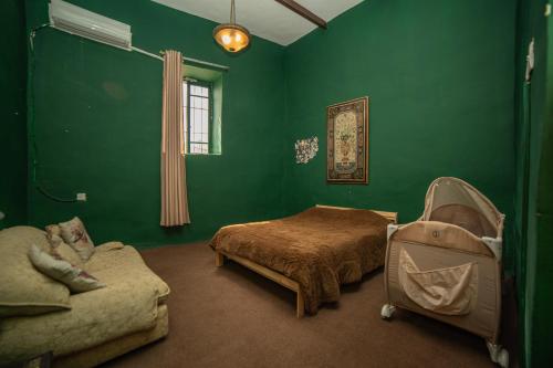 a bedroom with green walls and a bed and a couch at Central house with beautiful garden in Amman