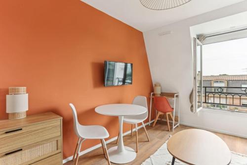une salle à manger aux murs orange avec une table et des chaises dans l'établissement Nice studio close to Paris, à Maisons-Alfort