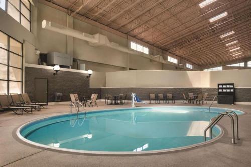 a large pool in a building with tables and chairs at Wyndham Garden Conference Center Champaign - Urbana in Champaign