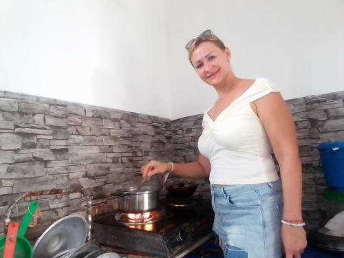 a woman is stirring a pot on a stove at Sisi's Place in Bentota