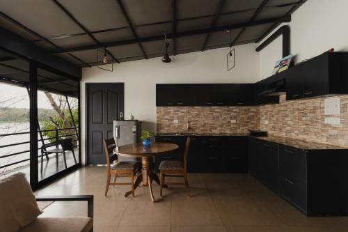 a kitchen with black cabinets and a table with chairs at Lakedale Resorts in Thekkumkara