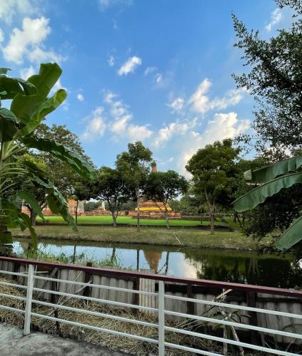 a pond in a park with trees and a fence at บ้านคุณยายอยุธยา in Phra Nakhon Si Ayutthaya