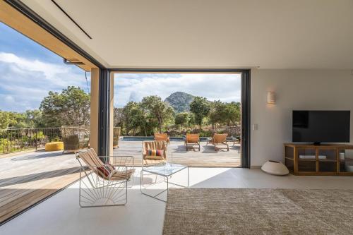 - un salon avec vue sur une terrasse et une télévision dans l'établissement Villa Paola, à Pianottoli-Caldarello