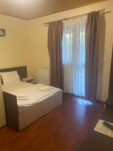 a bedroom with a bed and a window and a desk at Pensiunea Zece Brazi Cheia in Măneciu
