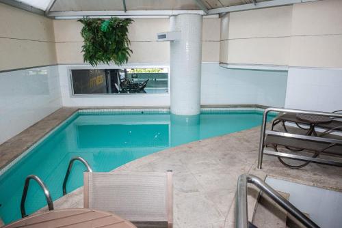 a swimming pool with chairs and a table and a table and chairsitures at Belo Horizonte Plaza in Belo Horizonte