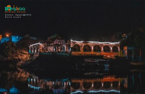 a house with lights on the water at night at Miskaa Nubian House in Naj‘ Tinjār