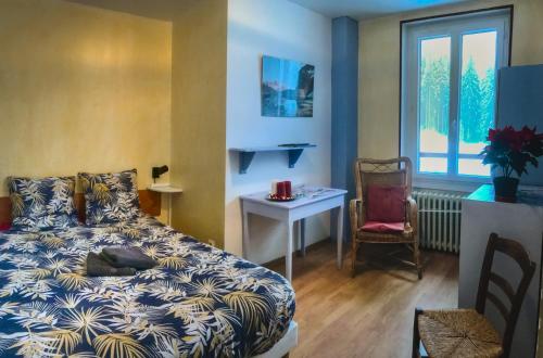 a bedroom with a bed and a table and a chair at Gite de la Martinette in La Ferrière