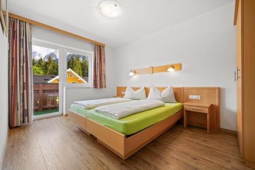 a bedroom with a bed and a window at Aparthotel Sunrise in Ramsau am Dachstein