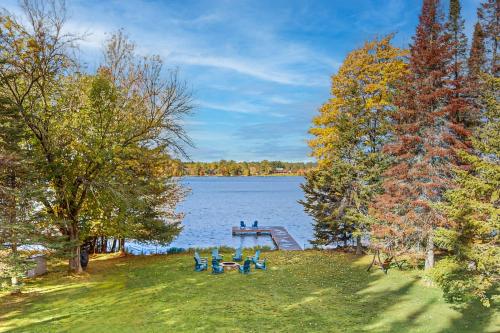 a dock on a lake with blue chairs and trees at Duck Lake Escape in Eagle River
