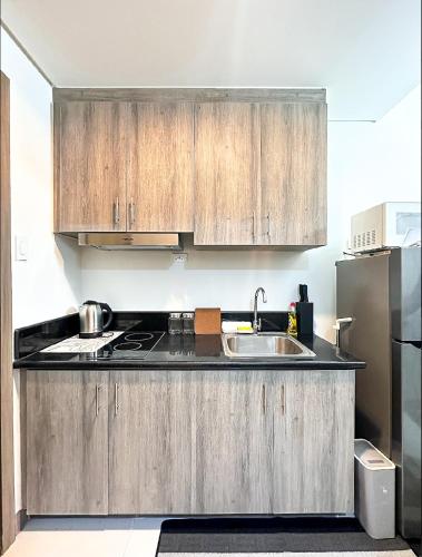 Una cocina con gabinetes de madera y un fregadero. en Cosy Deluxe Flat with Balcony near MOA, en Manila