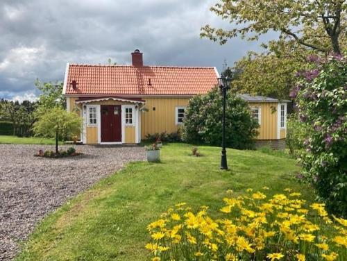 a yellow house with a red roof in a yard at Nice Home In Vikbolandet With 0 Bedrooms in Ursvik