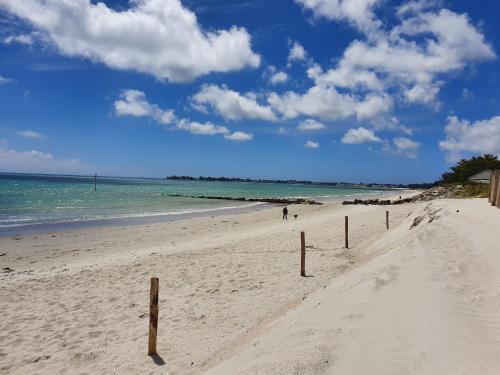a sandy beach with wooden poles in the sand at Escapade à Combrit in Combrit