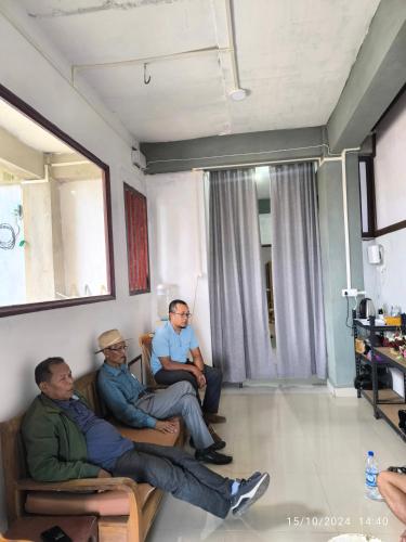 three men sitting on chairs in a room at Duhthang Run Backpackers Inn in Āīzawl