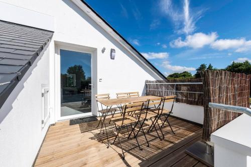 a wooden deck with a wooden table and chairs at Escapade à Combrit in Combrit
