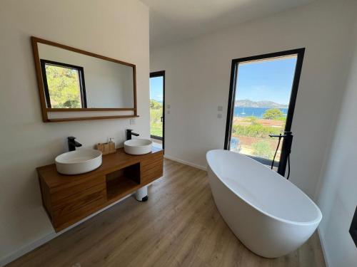 La salle de bains est pourvue de 2 lavabos et d'une grande baignoire. dans l'établissement Villa PERLE DE GIENS, à Hyères