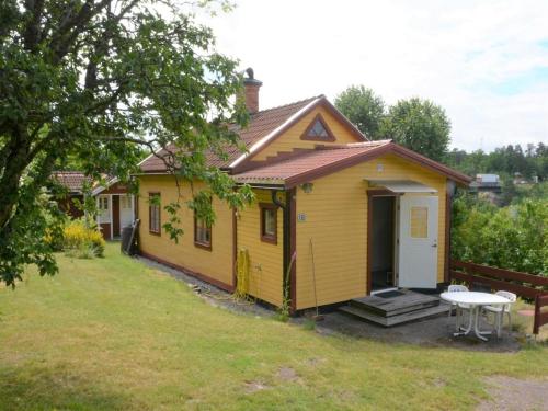 a small yellow house with a table in the yard at Awesome Home In Västervik With 1 Bedrooms in Västervik
