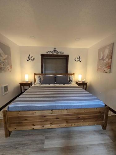 a bedroom with a large bed with two lamps on either side at Dovetail Den - Tranquil with Hot Tub and Air Conditioning in Ashford