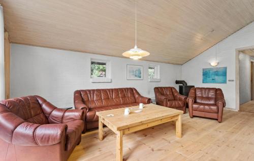 a living room with leather furniture and a wooden table at Nice Home In Blåvand With Sauna in Blåvand