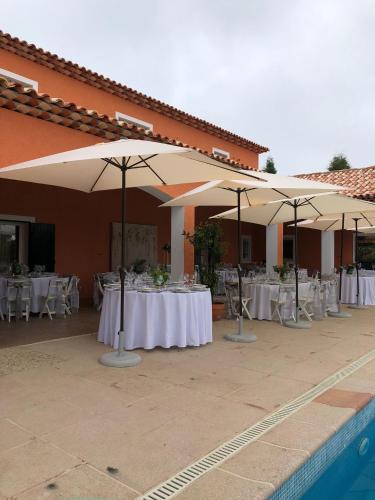 a group of tables with umbrellas next to a pool at Retiro dos Cedros - Quarto Adega in Fogueira