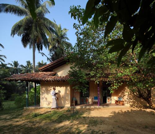 a woman standing in front of a house at Sama Retreats - Kosgoda in Kosgoda