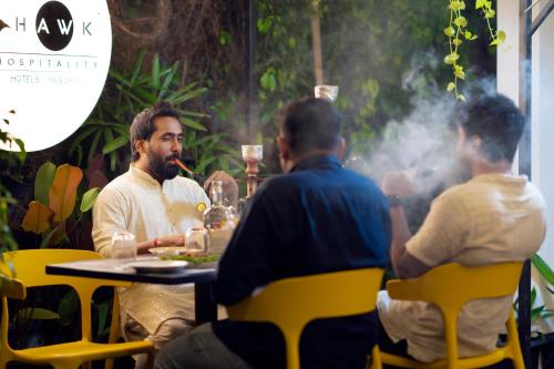 a group of people sitting around a table with smoke at Solo Inn By Hawk Hospitality in Cochin