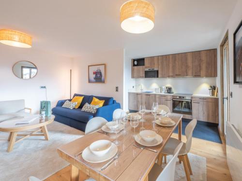 Il comprend une cuisine et un salon avec une table et un canapé bleu. dans l'établissement Appartement neuf 65m² proche centre-ville - 400m des pistes, Wi-Fi - FR-1-645-72, à Huez