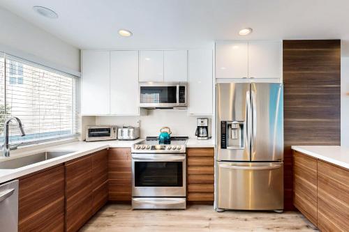 a kitchen with stainless steel appliances and wooden cabinets at Hale I'a in Carpinteria