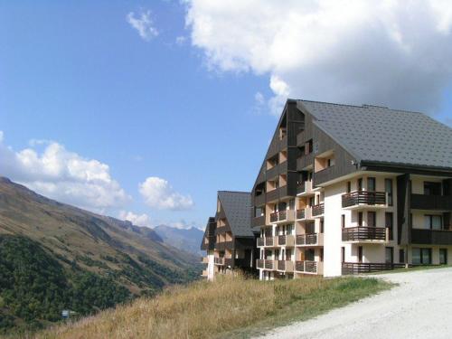 un bâtiment sur une colline à côté d'un chemin de terre dans l'établissement Charmant studio ski aux pieds avec parking aux Menuires - FR-1-452-91, aux Menuires