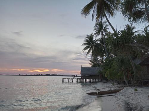 a beach with palm trees and a dock in the water at Fam Homestay in Fam