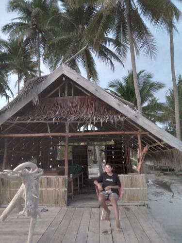 a man sitting in front of a hut on the beach at Fam Homestay in Fam