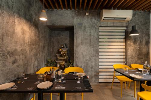 a dining room with tables and yellow chairs at Solo Inn By Hawk Hospitality in Cochin