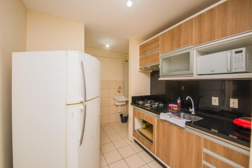 a kitchen with a white refrigerator and wooden cabinets at Apartamento completo ao lado da Arena Opus in Estêvão