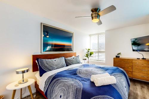 a bedroom with a blue bed and a flat screen tv at Hale I'a in Carpinteria