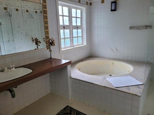 a bathroom with a tub and two sinks and a window at Villa Don in Petrópolis