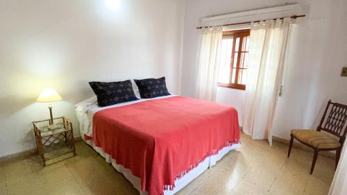 una camera da letto con un letto con una coperta rossa e una finestra di Bajando al Rio a Bella Vista