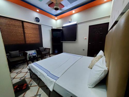 a bedroom with a large bed and a living room at Diplomat Inn Hotel in Karachi