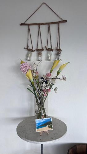 a vase of flowers on a table with a book at Casa dulce - Camaruche in Saint Barthelemy