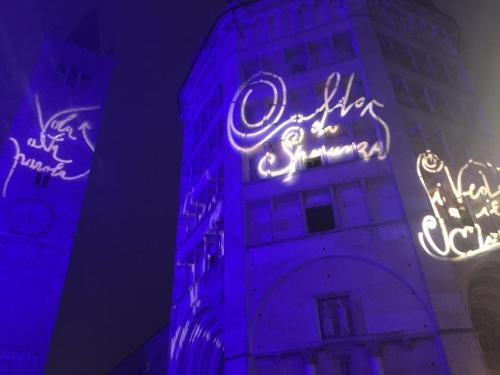 a tall building with neon signs on it at night at Apartment Ponte delle Nazioni in Parma