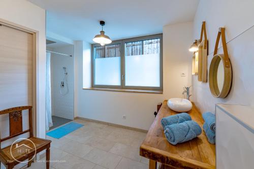 La salle de bains est pourvue d'une table et de serviettes bleues. dans l'établissement L'écrin de l'Astoria, à Tresserves