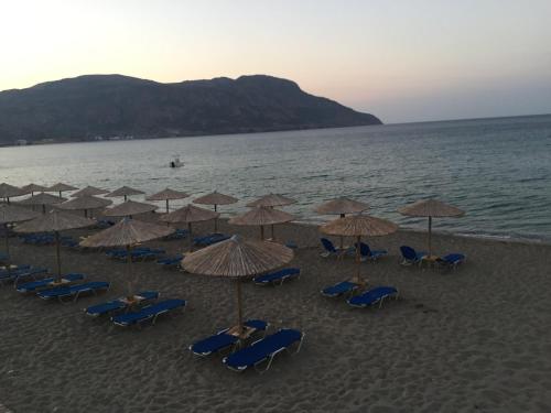 a group of chairs and umbrellas on a beach at Tamaris Suites in Karpathos Town