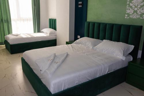 a bedroom with a large bed with a green headboard at EKAM Sun Apartments in Golem