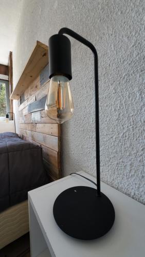 una lampada nera appoggiata su un tavolo bianco di Temiscira Hostel a San Carlos de Bariloche