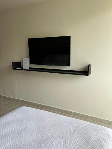 a flat screen tv on a wall with a shelf at New Business Centric Loft with gym and pool in Cancún