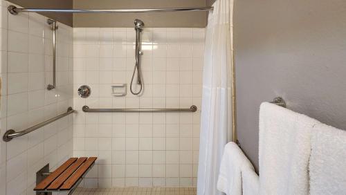 a bathroom with a shower with a wooden bench at Studio 6-Houston, TX - Hobby South in Houston
