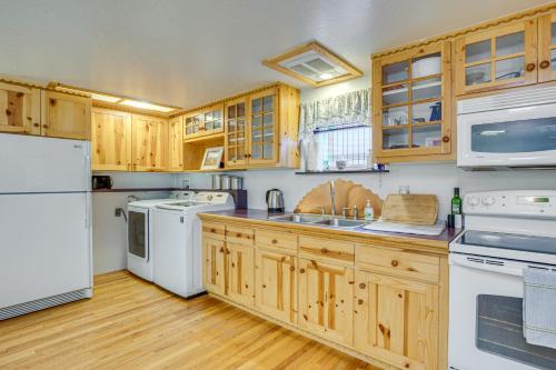Una cocina con electrodomésticos blancos y gabinetes de madera. en Near Hiking and Biking Home with Eckert Charm!, en Cedaredge