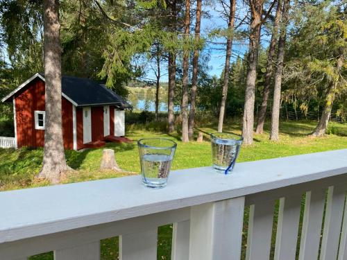 two glasses sitting on a rail on a porch at Sunshine Stuga Bergvik in Gällö