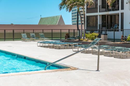 a swimming pool with lounge chairs and a swimming pool at Waikiki Banyan Fabulous Ocean View Condo with Free Parking in Honolulu